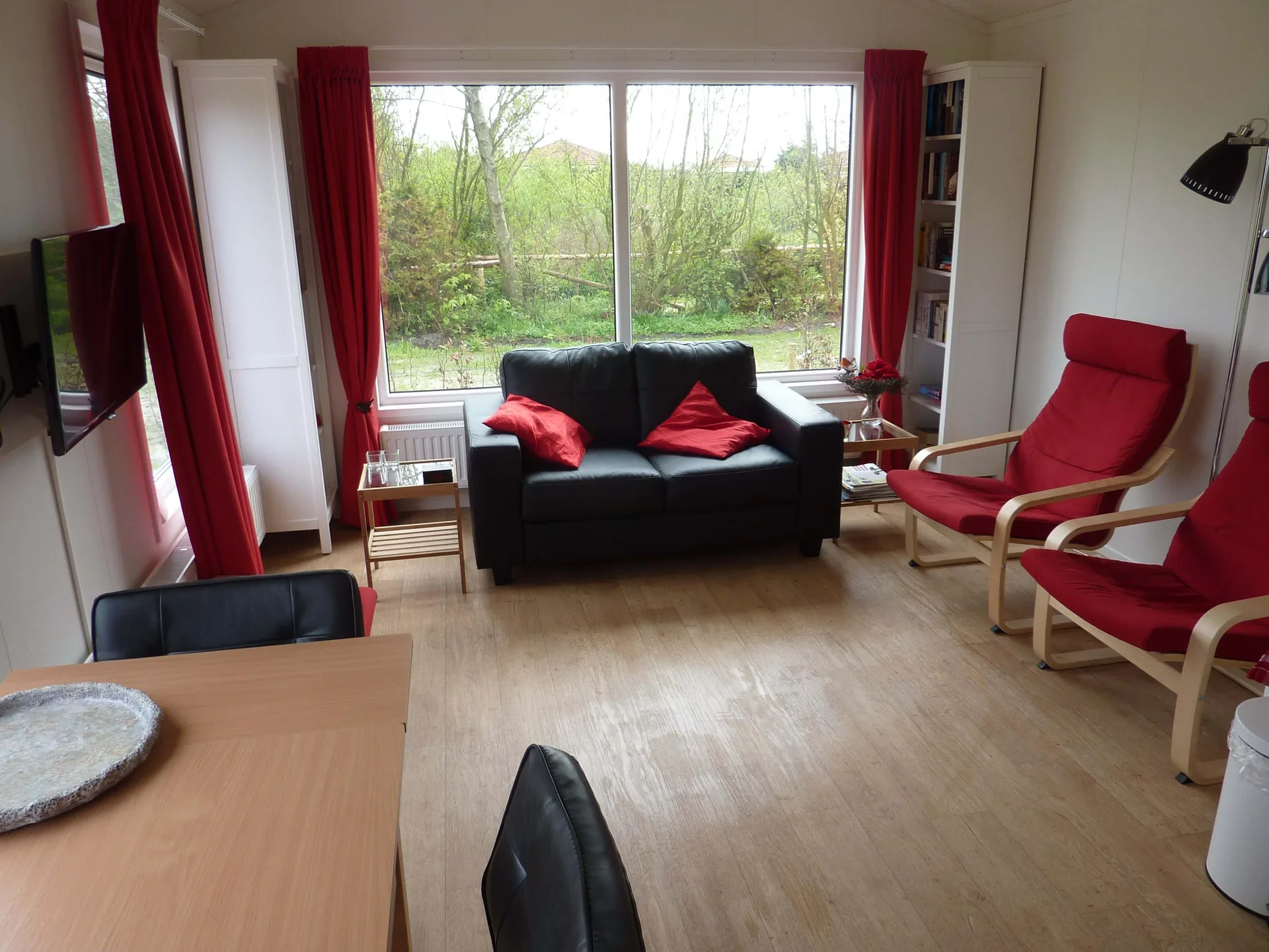 Lichte woonkamer met grote ramen en uitzicht op het groen